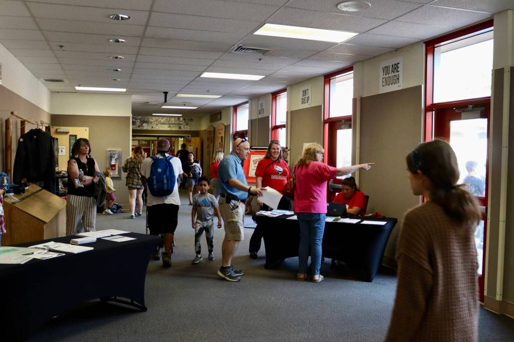 Kristy Germain, principal of Floyd Dryden Middle School, talks parents in the main lobby during the schools 50th anniversary open house celebration. School registrar Nikki Boghosian, seated, helps parents set up their power school accounts, where they can check grades. (Meredith Jordan / Juneau Empire)