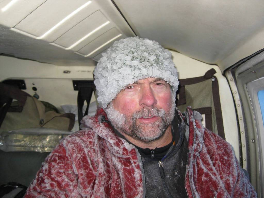 Volcano researcher John Paskievitch sits down coated in ice after three hours of creating and securing anchor points to tie off a Jet Ranger helicopter stranded by ice on the summit of Mount Mageik in the Valley of 10,000 Smokes. (Photo by Taryn Lopez)