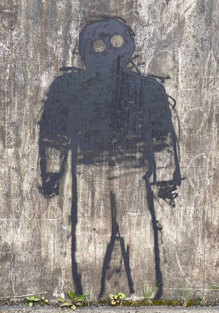 A hollow-eyed stranger watches passersby from the downtown bridge on Aug. 13. (Photo by Denise Carroll)