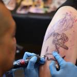 Ricardo Galindo tattoos a raven onto Juneau resident Sky Martin on Thursday afternoon at Elizabeth Peratrovich Hall during the Ink Masters Tattoo Show. (Clarise Larson / Juneau Empire)