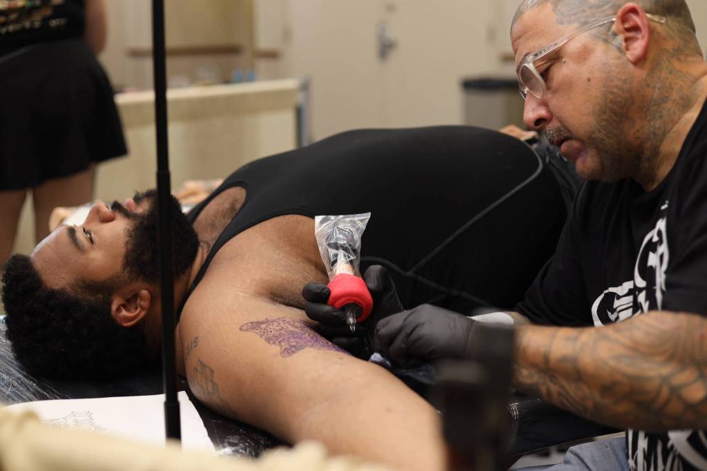 Juneau resident Taron Hampton gets a Lafayette leopard tattoo from Henry Bighead Lewis on Thursday afternoon at Elizabeth Peratrovich Hall during the Ink Masters Tattoo Show. (Clarise Larson / Juneau Empire)