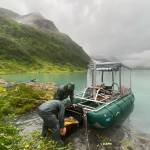 Drake Singleton, left, and Peter Haeussler install a sound wave-generating device onto a pontoon boat they carried to Allison Lake near Valdez. (Photo by Gerry Hatcher)