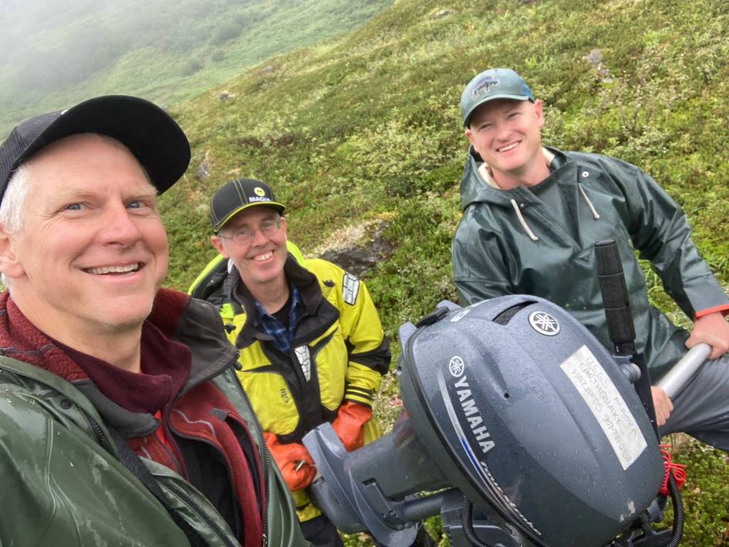 From left, Peter Haeussler, Gerry Hatcher and Drake Singleton carry a boat motor one-quarter mile to a lake they will study for signs of past earthquakes. (Photo by Peter Haeussler)