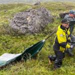 Gerry Hatcher, left, and Drake Singleton drag a deflated boat pontoon over wet vegetation to reach Allison Lake near Valdez. (Photo by Ned Rozell)