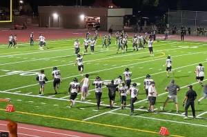 Juneau Huskies players and coaches storm the field in celebration after Hayden Aube runs for a touchdown in double overtime to win 55-49 at Washingtons Auburn State on Friday night. It was the first win of the season for Juneau, which returns home after a three-game road trip for another night game next Friday. (Screenshot from Juneau Huskies Football video)