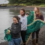 Participants in the 38th Annual International Coastal Cleanup carry a fishnet to a boat on a coast near Sitka in August. (Ryan Morse / Sitka Conservation Society)