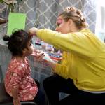 Angel White, 2, gets her face painted by Jennifer Skinner inside St. Vincent de Paul Juneaus Teal Street complex on Saturday as part of a Friends of the Poor Run/Walk to raise money for the facility and its programs. (Mark Sabbatini / Juneau Empire)