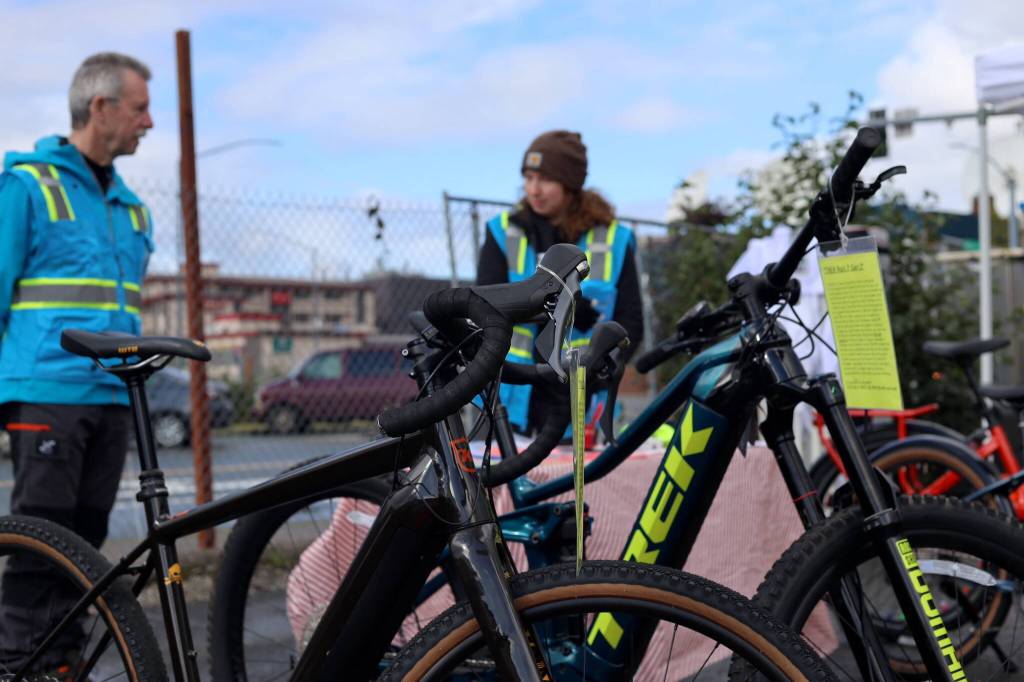 John McConnochie, co-owner of Cycle Alaska, and Ter Schnetter, retail manager, stand near a row of e-bikes for sale at Juneaus EV & E-bike Roundup downtown Saturday afternoon. (Clarise Larson / Juneau Empire)