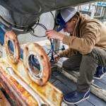 Lane Bolich, captain of the Harmony, reattaches a new hose for the boats tendering tanks, Saturday, June 24, 2023, in Kodiak, Alaska. After working as a deckhand for two years, he took the wheel as captain this year at just 20 years old. (AP Photo/Joshua A. Bickel)