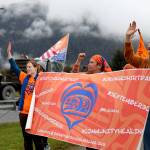 Residents hold signs and wave to cars as they pass by on Glacier Highway near the Mendenhall Wetlands viewing area in Juneau on Saturday morning during an Orange Shirt Day event. (Clarise Larson / Juneau Empire)