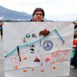 Linda Jacobs holds up a hand-painted sign she made early Saturday morning before attending the Orange Shirt Day morning flag wave near the Mendenhall Wetlands viewing area in Juneau on Saturday morning. (Clarise Larson / Juneau Empire)
