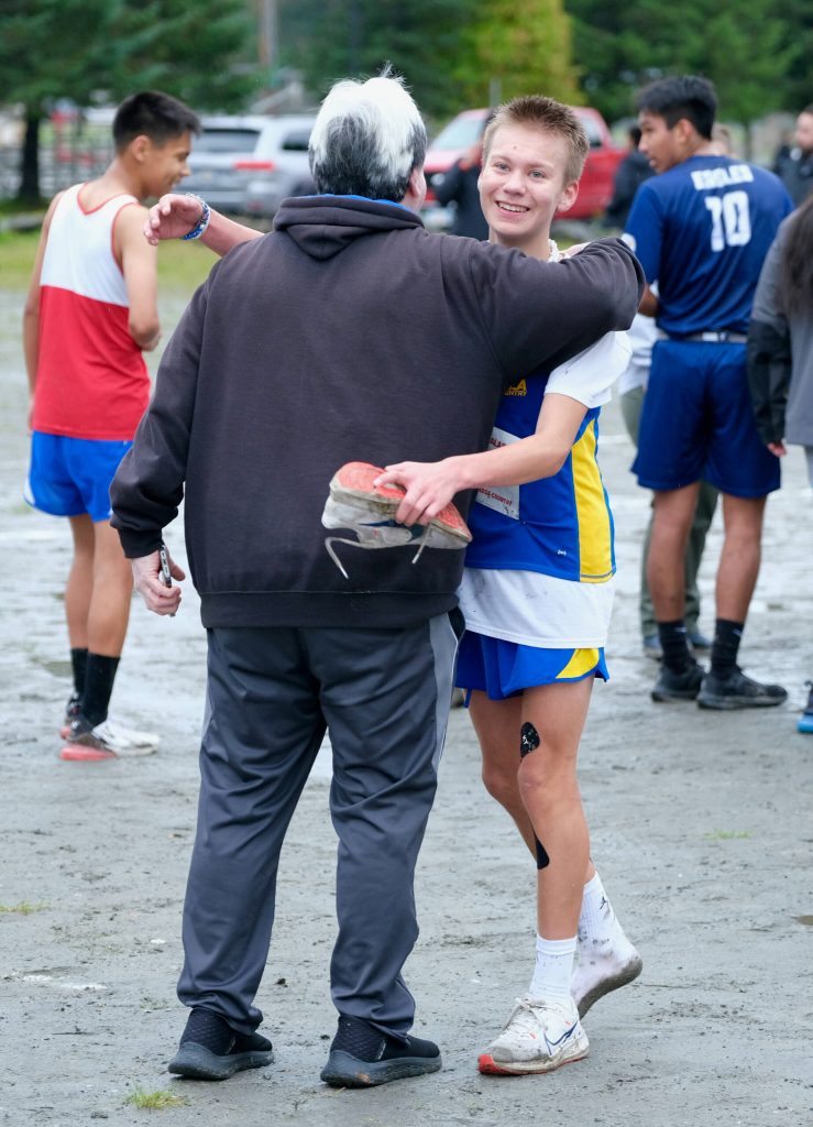 Metlakatla freshman George Peratrovich hugs uncle Tom Brendible after finishing with one shoe in the Division III Region V Boys Cross Country Championship race on Saturday at Treadwell Mine Trails. (Klas Stolpe / For the Juneau Empire)