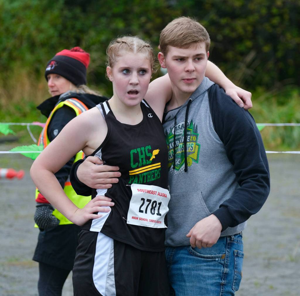 Craig High School freshman Ashlynn Smith is supported by brother Kyle Smith at the finish of the Division III Region V Girls Cross Country Championship race on Saturday at Treadwell Mine Trails. (Klas Stolpe / For the Juneau Empire)