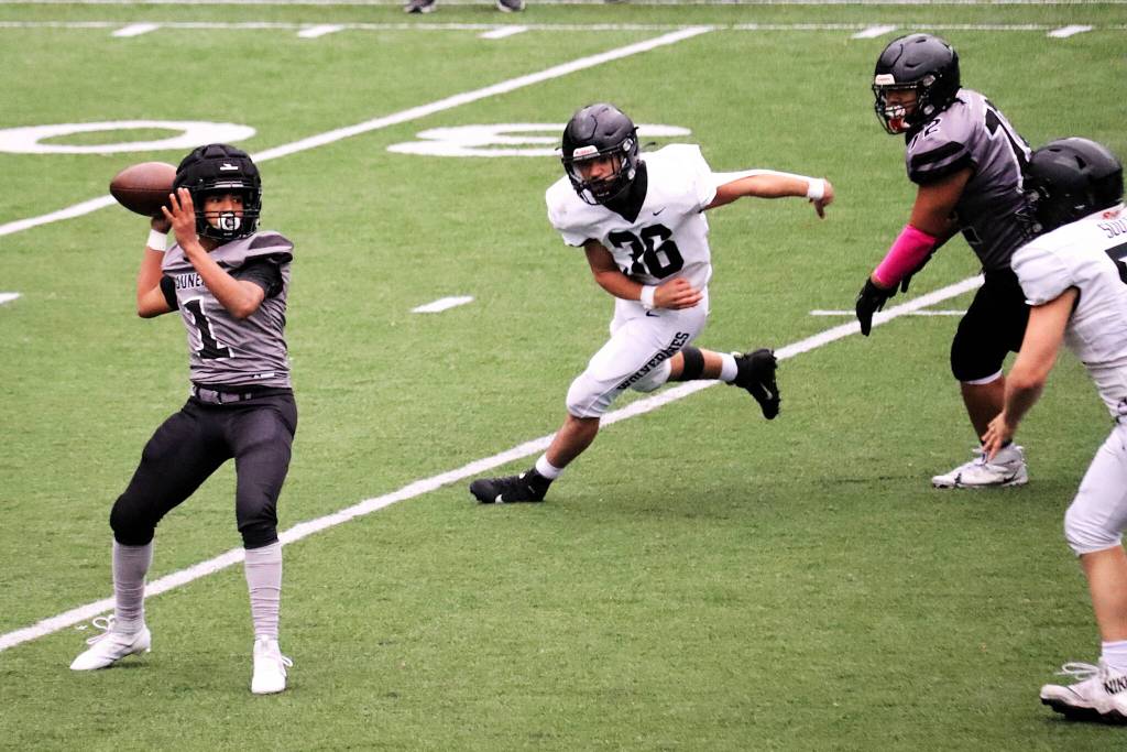 Noah Ault, a sophomore quarterback for Juneau, looks to pass under pressure against Anchorage South High School on Saturday at Adair-Kennedy Field. (Mark Sabbatini / Juneau Empire)