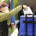 Editha Harris drops her ballot in the ballot box at the voter center located at the Mendenhall Valley Public Library on Tuesday afternoon. (Clarise Larson / Juneau Empire)