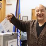 Michael Beasley smiles as he drops a ballot into a drop box at the City Hall Assembly Chambers on Election Day Tuesday morning. (Clarise Larson / Juneau Empire)