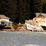 A home hangs over the edge of an eroded riverbank after part of the neighboring house fell into the Mendenhall River during the record flooding of Suicide Basin on Aug. 5. The rest of the second home was later demolished. (Mark Sabbatini / Juneau Empire File)