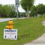 A sign opposing the participation of transgender girls in girls sports is propped against a fire hydrant outside of the George A. Navarre Admin Building on Thursday, June 8, 2023, in Soldotna. (Ashlyn OHara/Peninsula Clarion)