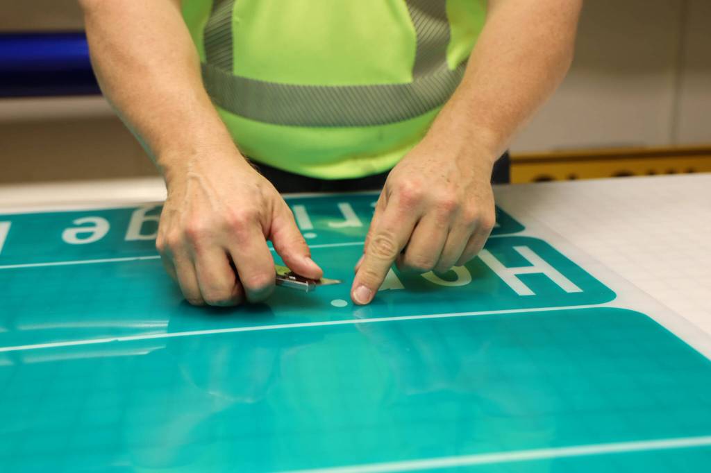 Chris Anderson removes the vinyl letters cut out for the new Heritage Way signs in the making ahead of the South Seward Street name change Nov. 1. (Clarise Larson / Juneau Empire)