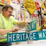 Chris Anderson mounts a Marine View and Heritage Way sign together in preparation for the South Seward Street name change Nov. 1. (Clarise Larson / Juneau Empire)