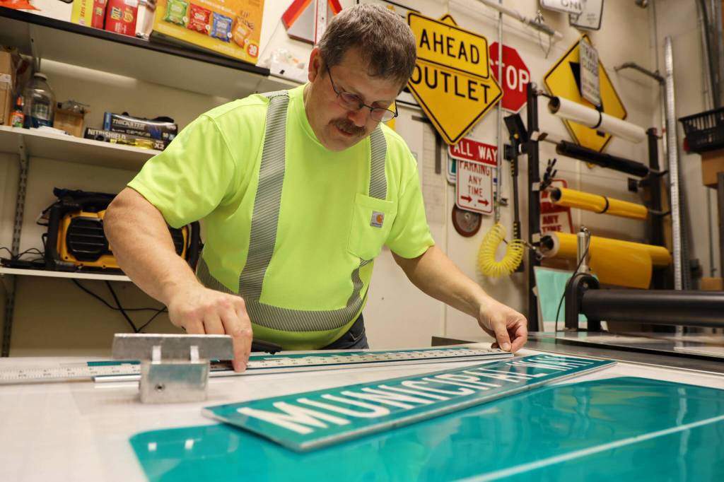 Chris Anderson measures a Heritage Way in preparation for the South Seward Street name change Nov. 1. (Clarise Larson / Juneau Empire)