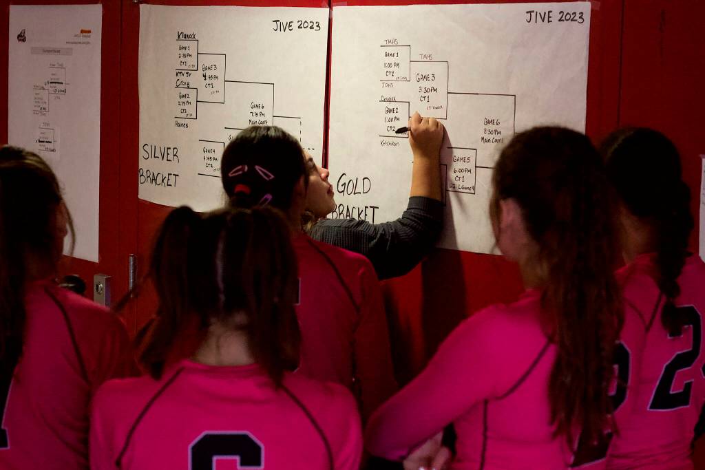 A Chugiak High School player writes the schools name into the next round of Gold Bracket play after the team won its first game of the double-elimination portion of the Juneau Invitational Volleyball Extravaganza at Juneau-Douglas High School: Yadaa.at Kalé on Saturday. (Mark Sabbatini / Juneau Empire)
