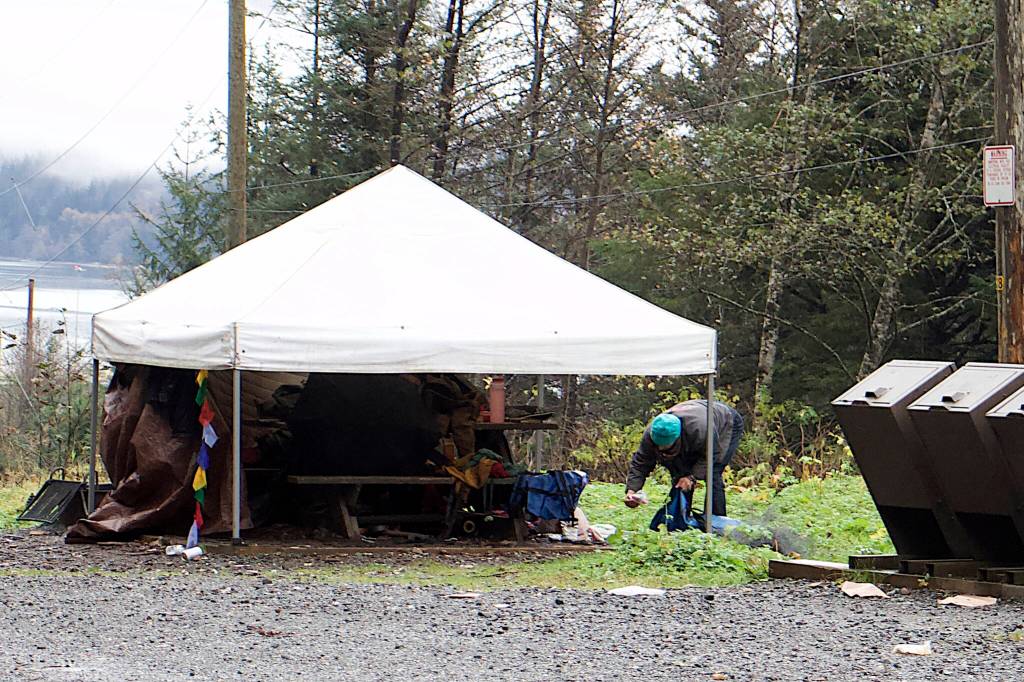 A resident at Mill Campground looks through items to keep and discard on the ground near the meal shelter on Sunday. (Mark Sabbatini / Juneau Empire)