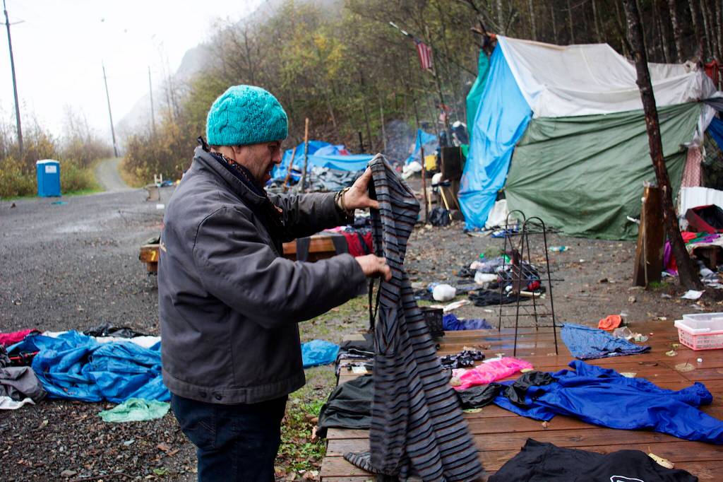 Garrett Derr, a resident at Mill Campground, examines a hoodie left on a tent platform by a former occupant on Sunday, the day before the campground closed for the season. Numerous residents left ahead of the closing date, leaving large amounts of possessions and trash behind. (Mark Sabbatini / Juneau Empire)