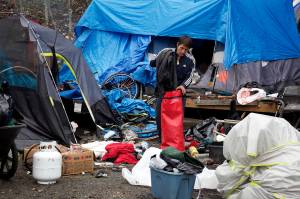 Albert Dick packs belongings into a dry bag at Mill Campground shortly before its official closing for the season at noon Monday. Many people experiencing homelessness who were staying the campsite this summer left before the final day due to problems such as bears ransacking tents. (Mark Sabbatini / Juneau Empire)