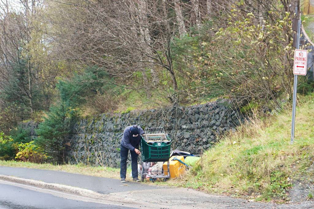 A person loads belongings on a shopping cart along the side of Thane Road at the turnoff to Mill Campground after it closed for the season at noon Monday. (Mark Sabbatini / Juneau Empire)