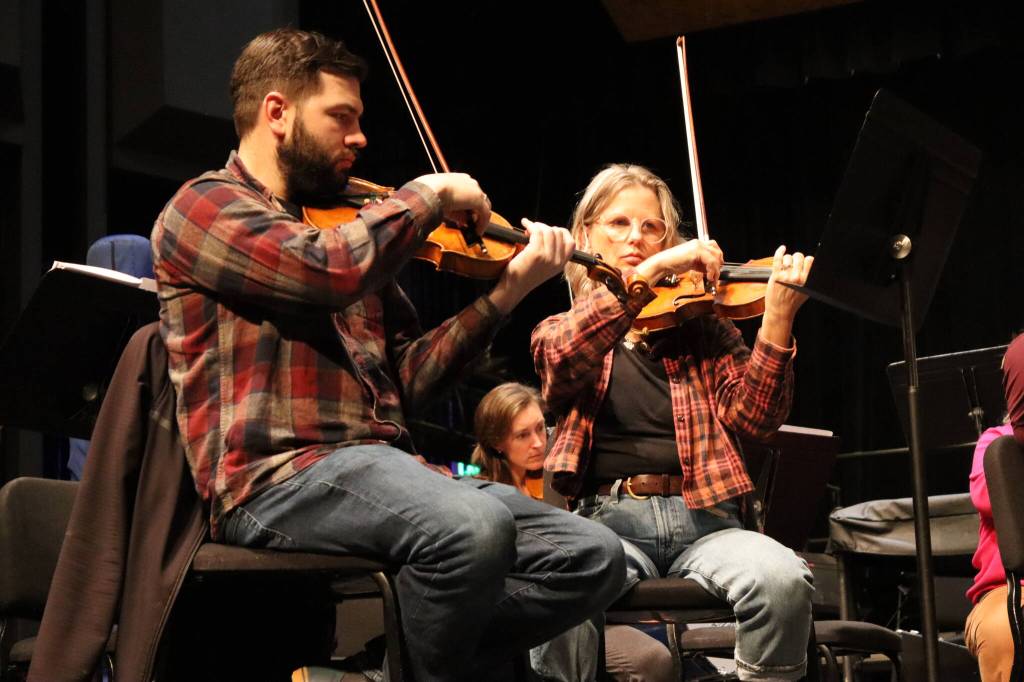 Violinists Franz Felkl and Lisa Ibias of the Juneau Symphony focus on their parts in Candide at rehearsal on Tuesday at Juneau-Douglas High School: Yadaa.at Kalé. (Meredith Jordan/ Juneau Empire)