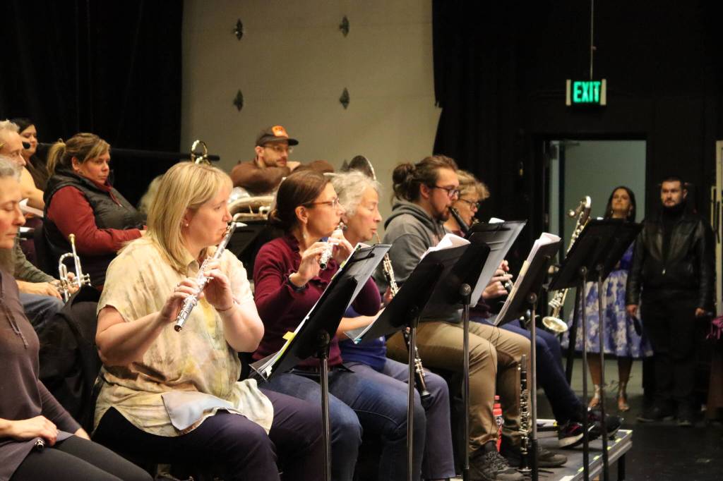 Candide cast members Skiba Wuoti (Cunegonde) and Steven Arends (Maximilian) stand in the wings watching the woodwind section rehearse on Tuesday at Juneau-Douglas High School: Yadaa.at Kalé. (Meredith Jordan/ Juneau Empire)