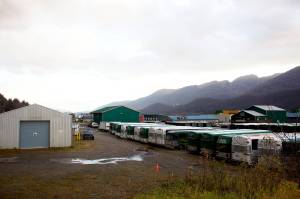 Rows of tour buses are parked Thursday next to a city-owned warehouse, at left, a portion of which is scheduled to open as a winter warming shelter starting Friday night. Some businesses managers and employees in the area say people experiencing homelessness have been found sleeping on busses and engaging in other disruptive activity, which is prompting an increase in security and other precautions in preparation for the shelters opening. (Mark Sabbatini / Juneau Empire)