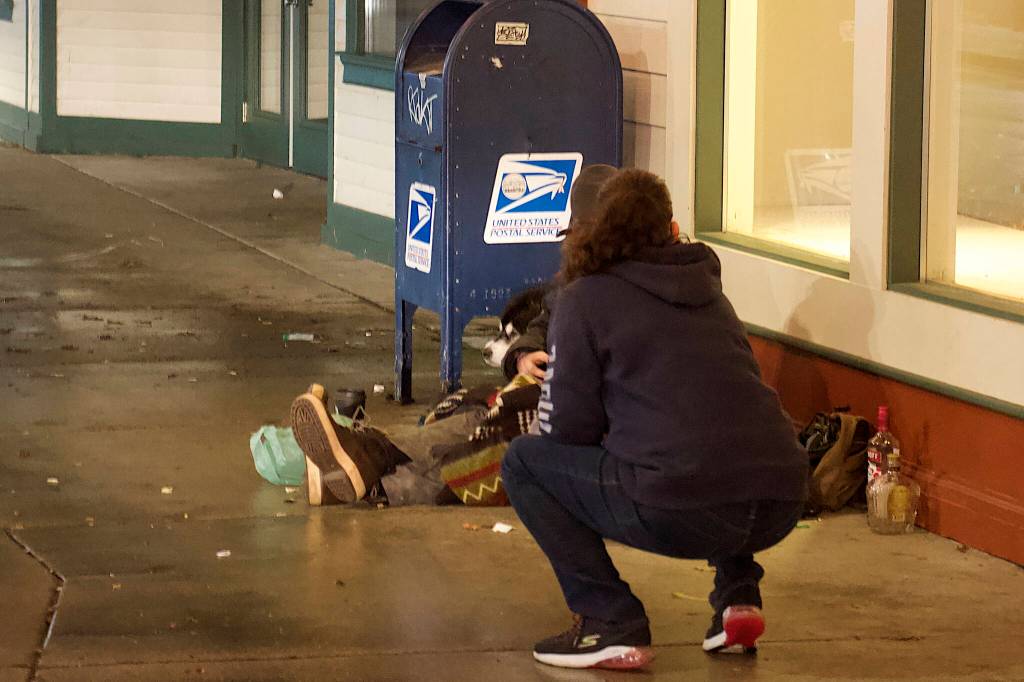 Carie Simons, a staff member at the citys new cold weather emergency shelter, offers a person sitting on South Franklin Street a ride aboard a shuttle bus to the shelter on Friday night. (Mark Sabbatini / Juneau Empire)