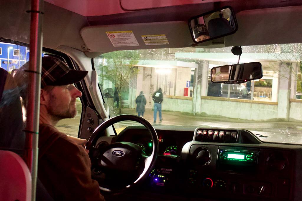 Travis Johnson, a staff member at the citys new cold weather emergency shelter, drives a shuttle van through downtown Juneau on Friday night in search of people who might want a ride to the facility to spend the night. (Mark Sabbatini / Juneau Empire)