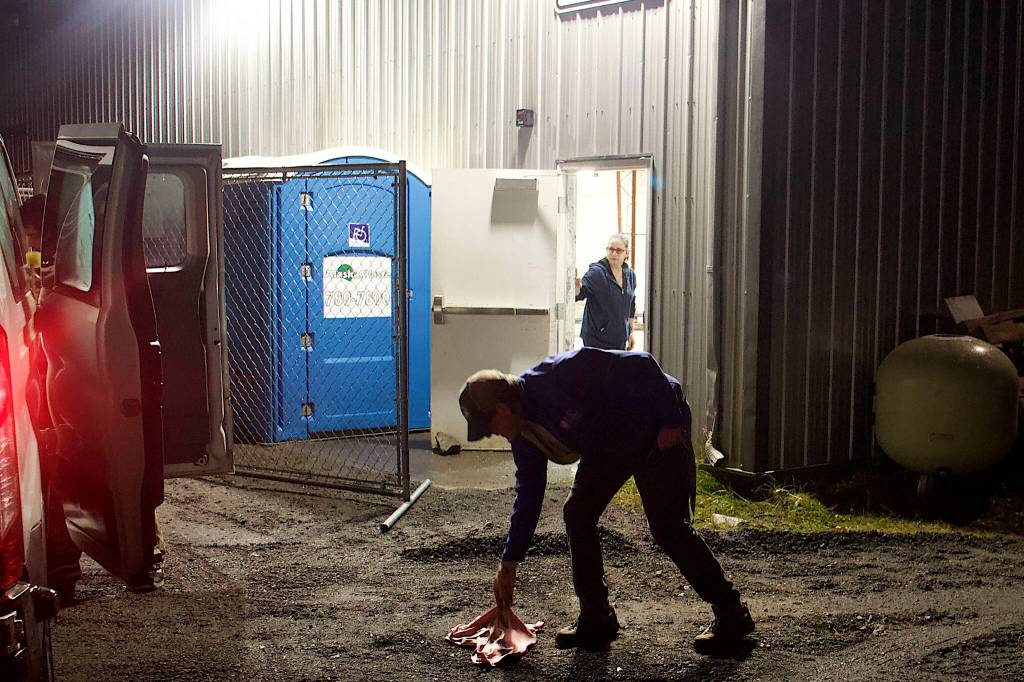 Dave Ringle, executive director of St. Vincent de Paul Juneau, picks up an item dropped by a person arriving at the citys new cold weather emergency shelter on Friday night. SVDP is operating the shelter in a city-owned warehouse about a mile south of downtown Juneau. (Mark Sabbatini / Juneau Empire)