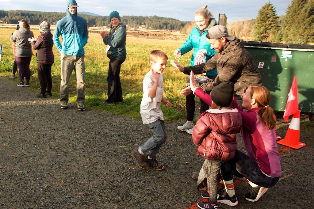 Holden Field, 7, high-fives his parents, Garrison and Brooke, after completing the kids half-mile race during the second annual Real Talk Walk/Run on Saturday at the Airport Dike Trail. (Mark Sabbatini / Juneau Empire)