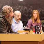 Shane Krause, left, who lives aboard a boat in Juneau, testifies in opposition to a 9% increase in docks and harbor fees during an Assembly meeting on Monday night as Deputy City Manager Robert Barr, City Manager Katie Koester and City Attorney Robert Palmer listen. (Mark Sabbatini / Juneau Empire)