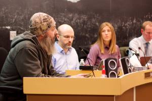 Shane Krause, left, who lives aboard a boat in Juneau, testifies in opposition to a 9% increase in docks and harbor fees during an Assembly meeting on Monday night as Deputy City Manager Robert Barr, City Manager Katie Koester and City Attorney Robert Palmer listen. (Mark Sabbatini / Juneau Empire)