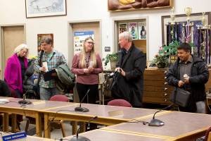Newly-sworn Juneau Board of Education members Britteny Cioni-Haywood and David Noon (left) prepare to take their seats as outgoing members Brian Holst and Martin Stepetin Sr. (right) depart during the boards meeting Tuesday night at Juneau-Douglas High School: Yadaa.at Kalé. At center, Jessica Richmond, administrative assistant to the Juneau School District superintendent, replaces the name signs of the board members at the two seats. (Mark Sabbatini / Juneau Empire)