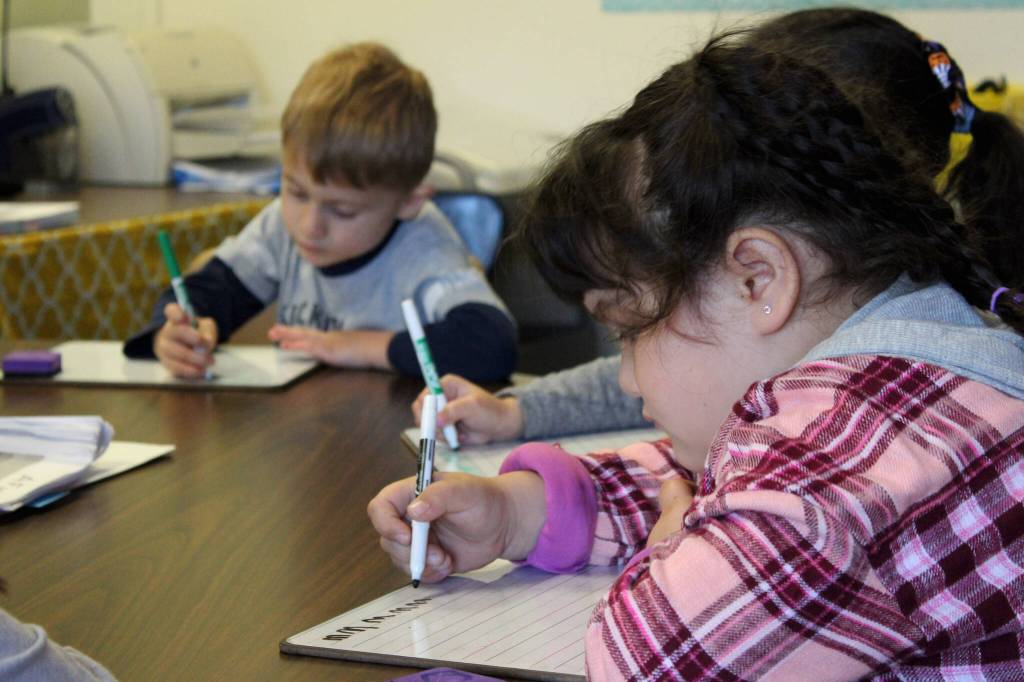 Students practice writing the letter M during a group activity led by Mountain View Elementary School Interventionist Katie Schneider on Thursday, Oct. 19, 2023, in Kenai, Alaska. (Ashlyn OHara/Peninsula Clarion)