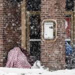 Two people take cover in an entryway of a downtown restaurant on Fourth Avenue on Thursday in Anchorage. Four homeless people have died in Anchorage in the last week, underscoring the citys ongoing struggle to house a large houseless population at the same time winter weather has returned, with more than 2 feet (0.61 meters) of snow falling within 48 hours. (Marc Lester/Anchorage Daily News via AP)