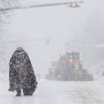 A pedestrian takes cover under a blanket on Cordova Street as plows clear the roadway on Thursday in Anchorage. Four homeless people have died in Anchorage in the last week, underscoring the citys ongoing struggle to house a large houseless population at the same time winter weather has returned, with more than 2 feet (0.61 meters) of snow falling within 48 hours. (Marc Lester/Anchorage Daily News via AP)
