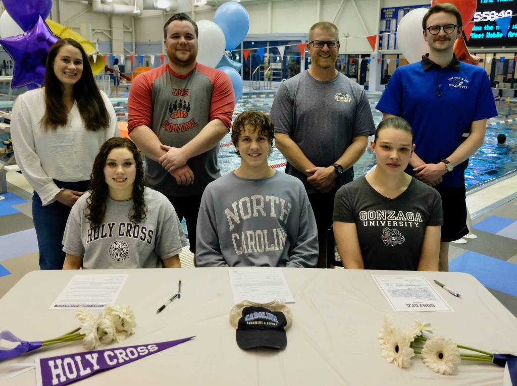 Juneau-Douglas High School: Yadaa.at Kalé senior Samantha Schwarting and Thunder Mountain High School seniors PJ Foy and Olivia Mills are joined by (standing left-right) Crimson Bears coaches Amber Kelly and Seth Cayce, Glacier Swim Club coach Scott Griffith and Falcons coach Josiah Loseby during their National Letter of Intent (NLI) signing on Tuesday at the Dimond Park Aquatic Center. (Klas Stolpe for the Juneau Empire)