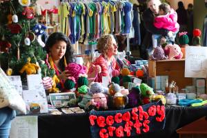 Rebecca Hsieh, left, knits small gifts as a first-time vendor at the Juneau Public Market as her friend, MK MacNaughton, a longtime vendor sells hand-painted items near the entrance of Centennial Hall on Nov. 26, 2022. (Mark Sabbatini / Juneau Empire File)