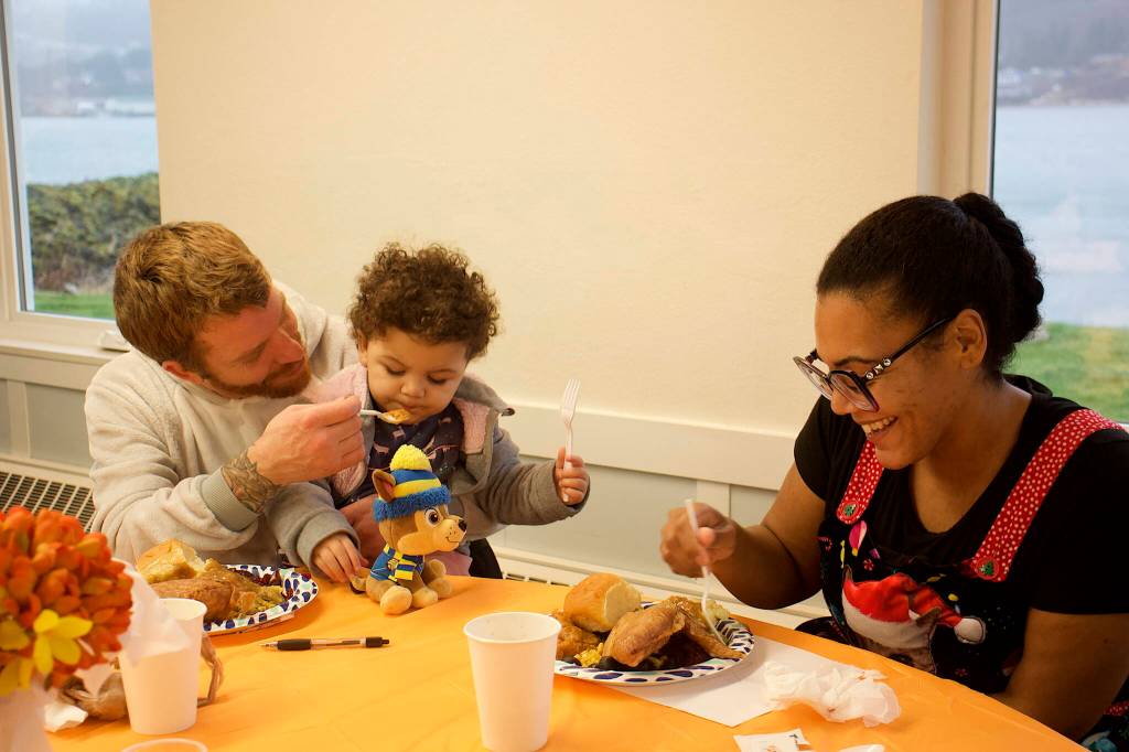 Mark Sabbatini / Juneau Empire
Joshua Smith, 22-month-old Aira Smith and Karli Phillips share a table at the communal Thanksgiving dinner hosted by The Salvation Army Juneau Corps at the Juneau Yacht Club on Thursday.