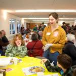Keeley Riley, a volunteer at the communal Thanksgiving dinner hosted by The Salvation Army Juneau Corps, offers takeout containers to a family of diners at the Juneau Yacht Club on Thursday. (Mark Sabbatini / Juneau Empire)