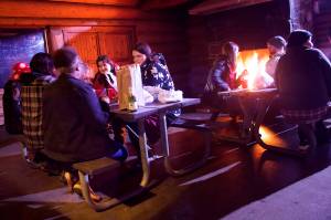 People gather for a newly organized communal Friendsgiving celebration at the log cabin at Savikko Park on Thursday night. (Mark Sabbatini / Juneau Empire)