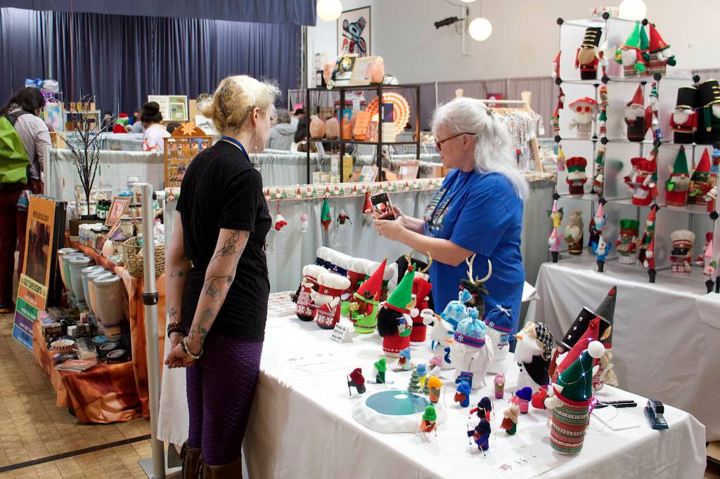 Vendors and shoppers mingle at the Juneau Public Market tables in the Juneau Arts and Culture Center on Friday. (Mark Sabbatini / Juneau Empire)