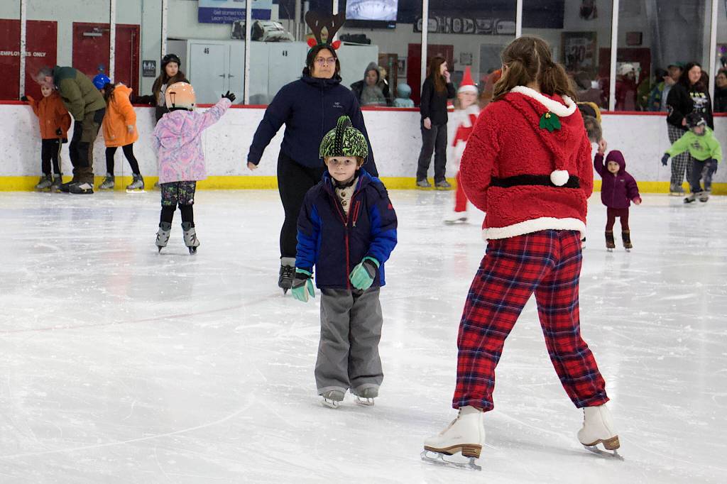 One of Santas helpers coaxes a skater along the ice during the annual Santa Skate at Treadwell Arena on Friday night.(Mark Sabbatini / Juneau Empire)